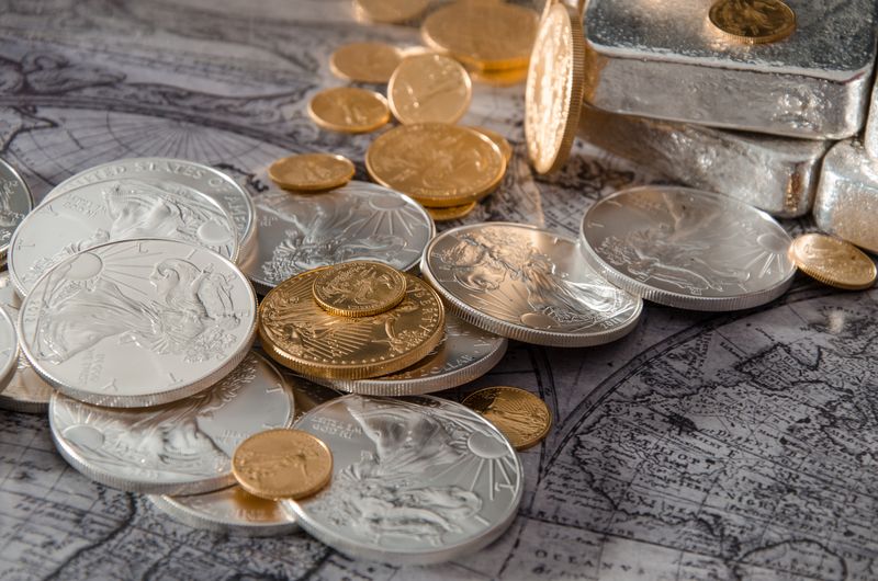 Silver bars with gold and silver coins on an old map, the kind of bullion a Denver seller brings to an appointment